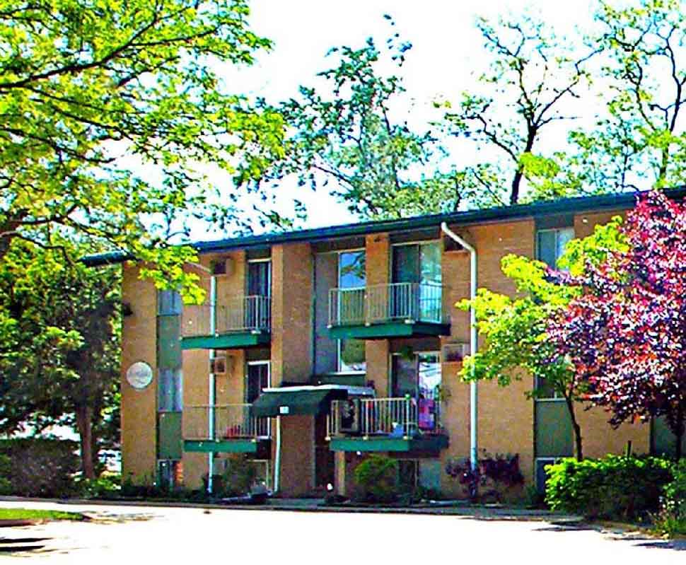 Apartment building with green trees in front.