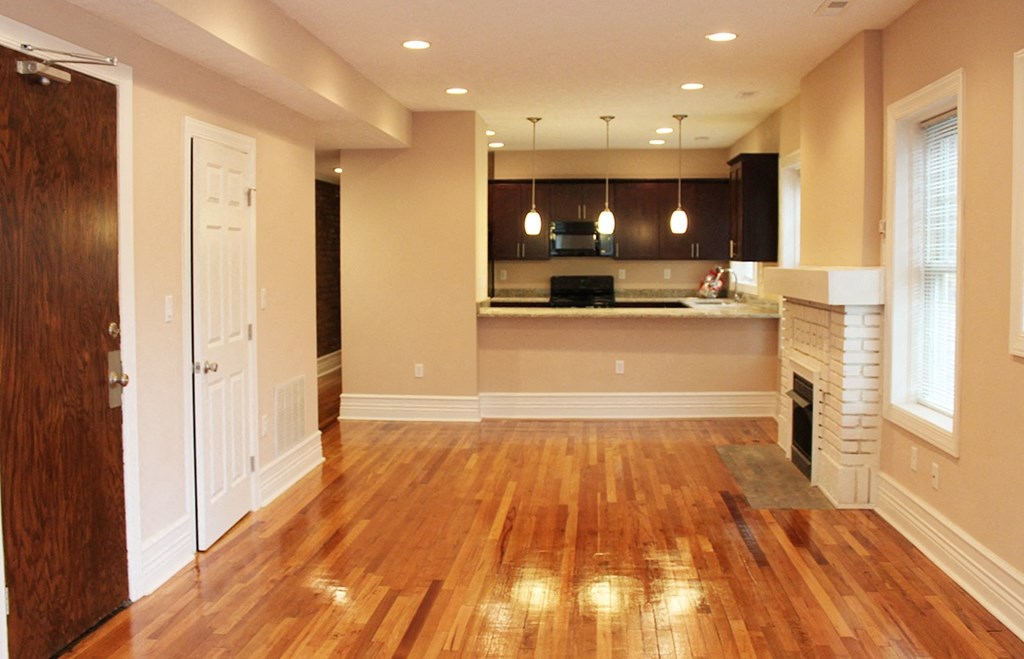 an empty living room and kitchen with wood floors