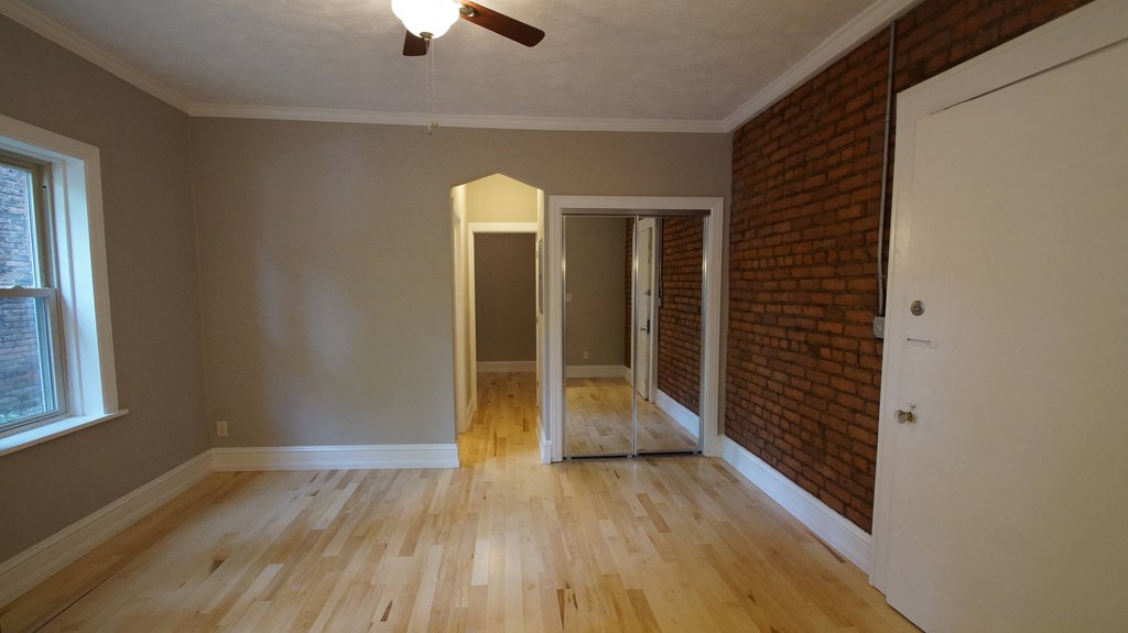 an empty living room with wood floors and a brick wall