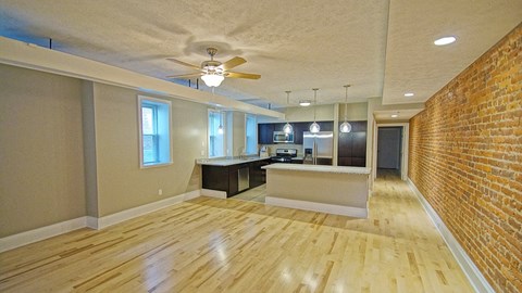 an empty living room with a brick wall and a ceiling fan