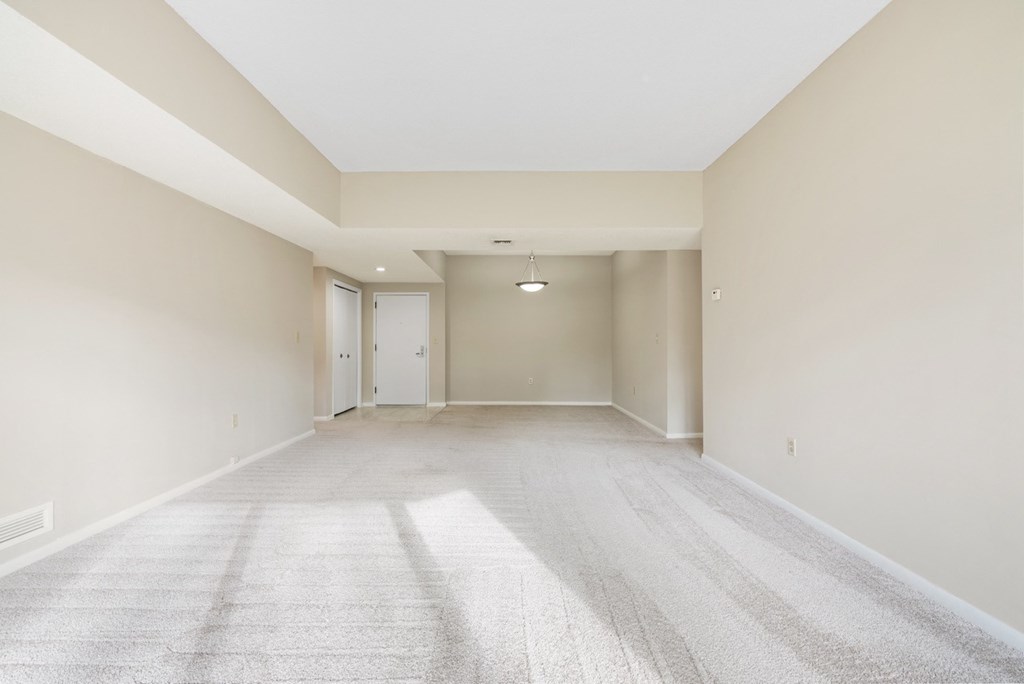A spacious living room with a carpeted floor and white walls.at Atrium in The Village, Ohio