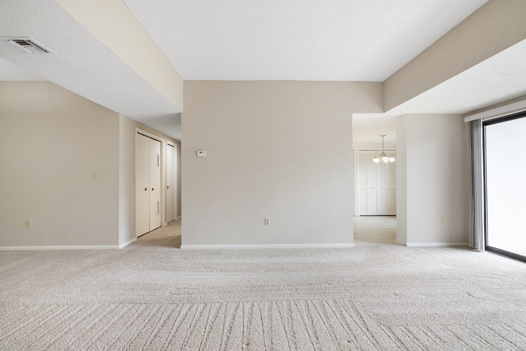 A large, empty room with a carpeted floor and a door on the left side.at Atrium in The Village, Beachwood, OH 44122