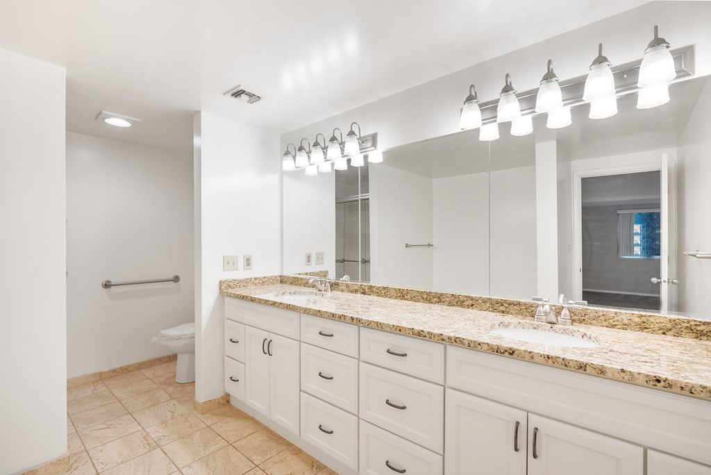 A bathroom with a marble countertop and a large mirror.at Atrium in The Village, Beachwood, OH