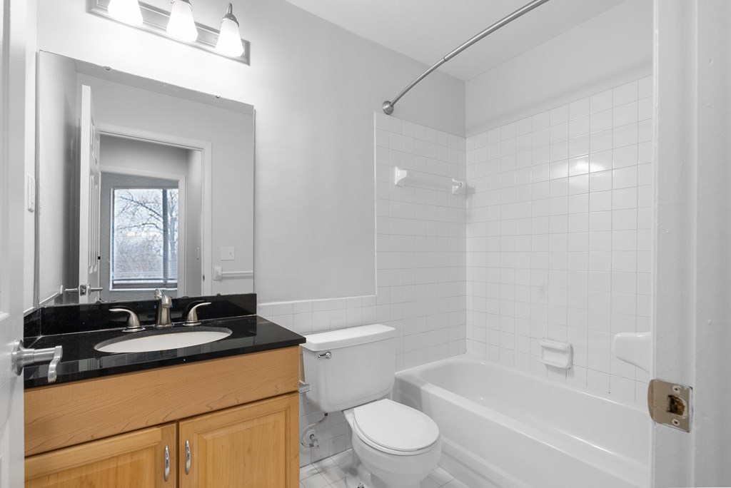 White bathroom with oak cabinet and black counter at Integrity Medina Apartments,  Ohio, 44256