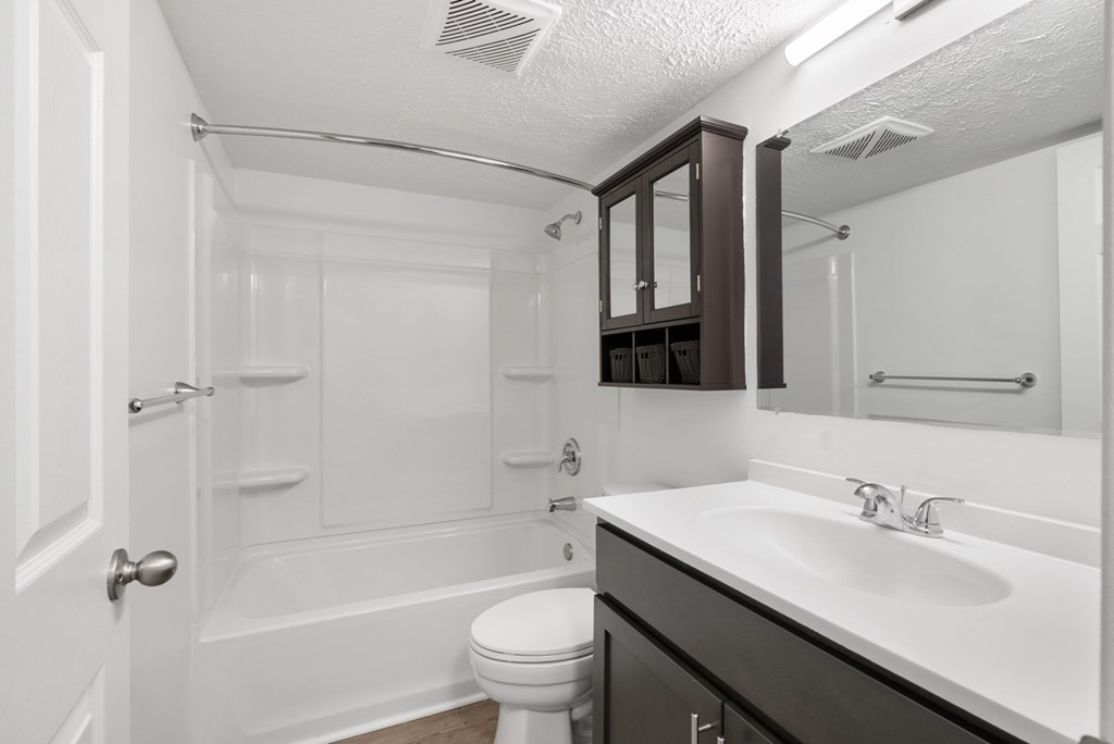 White bathroom with tub and espresso-colored cabinets at Integrity Medina Apartments, Medina, OH,  44256