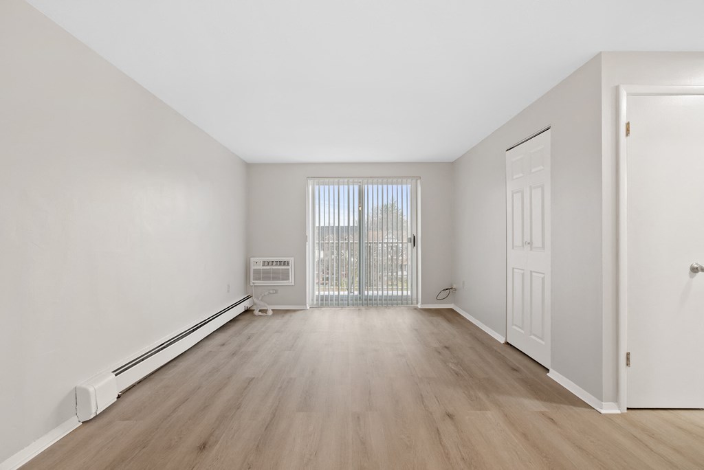 Living room with ash wood floors and sliding door to balcony.