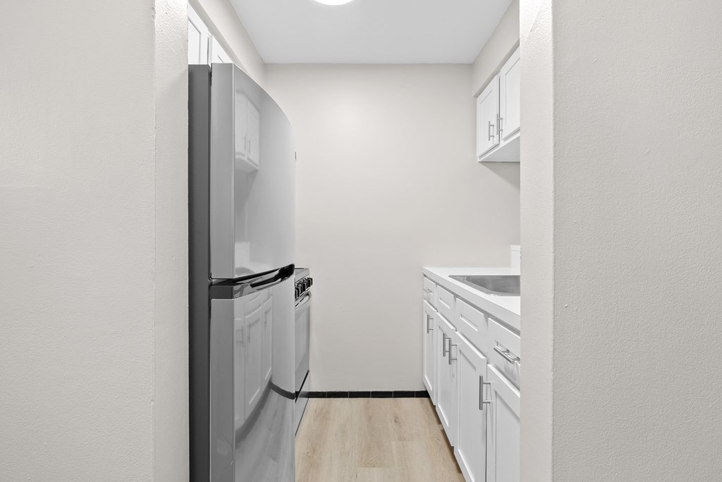 A kitchen with a refrigerator, oven, and cabinets.