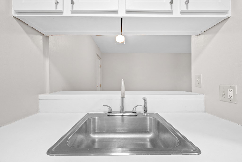 A modern kitchen with a stainless steel sink and white cabinets.