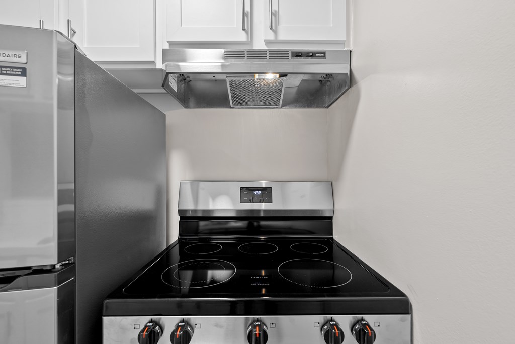 A modern kitchen with a stainless steel refrigerator and a black stove top.