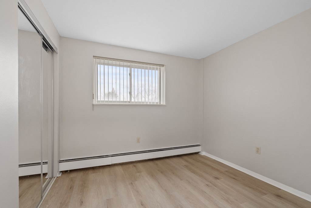 Bedroom with a window and wooden flooring.