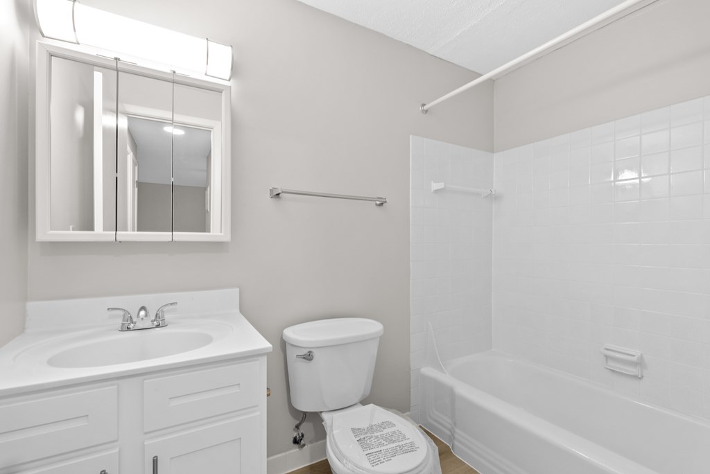 A white bathroom with a toilet, sink, and bathtub.
