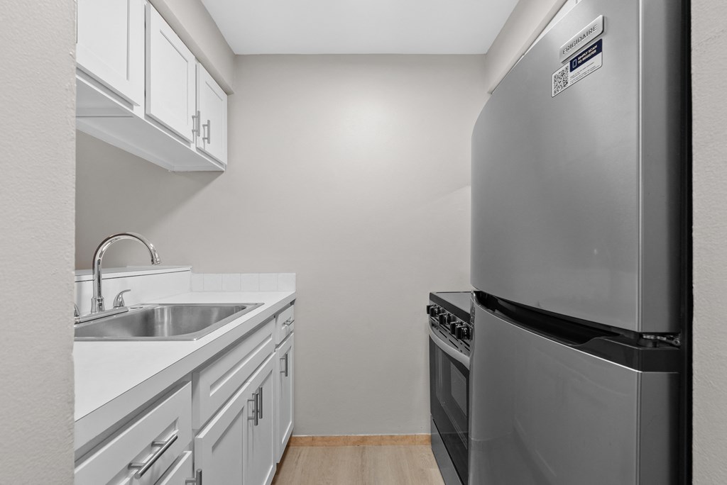 A kitchen with a stainless steel refrigerator and white cabinets.