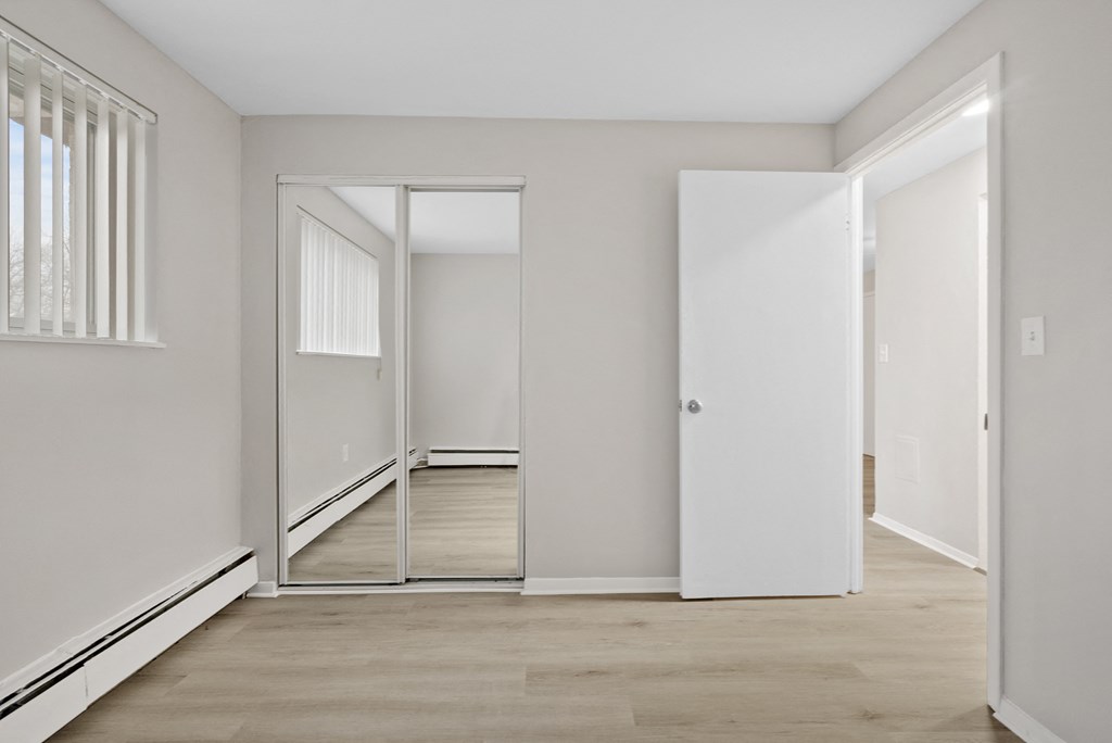 A bedroom with a mirrored closet.