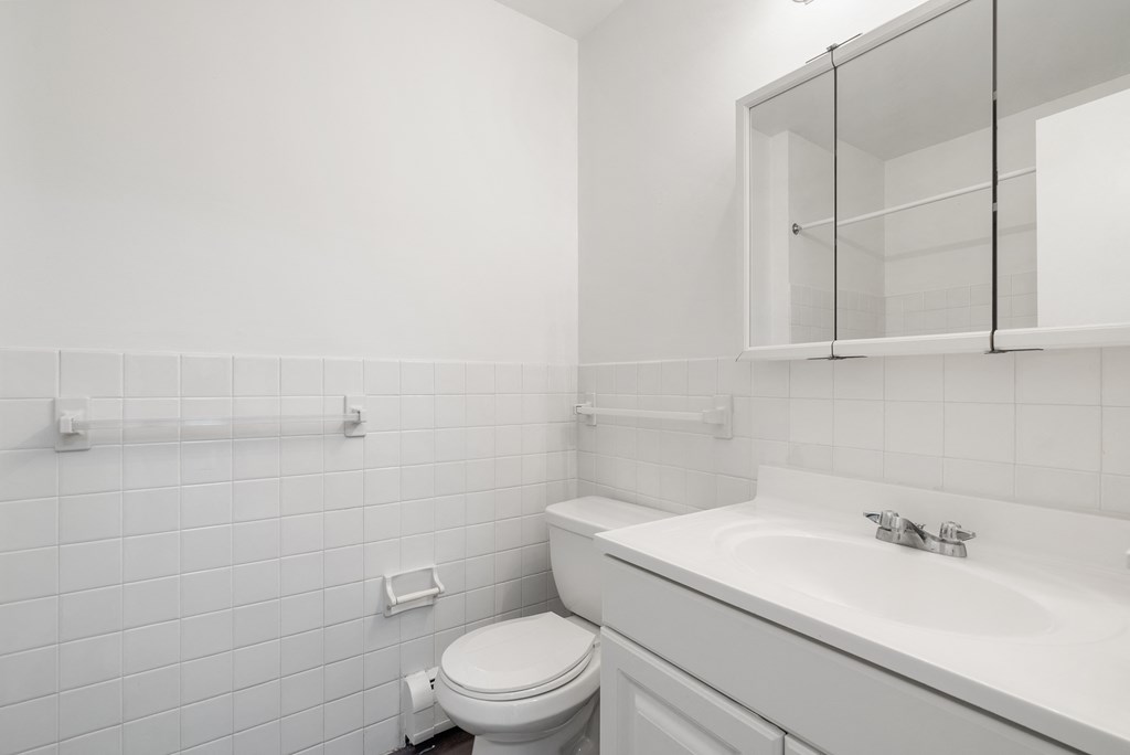 Updated Wynwood bathroom with white cabinets, counters, and tiling.