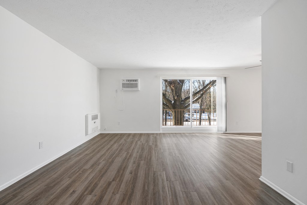 Updated Wynwood great room with sliding glass door to balcony and plank flooring.