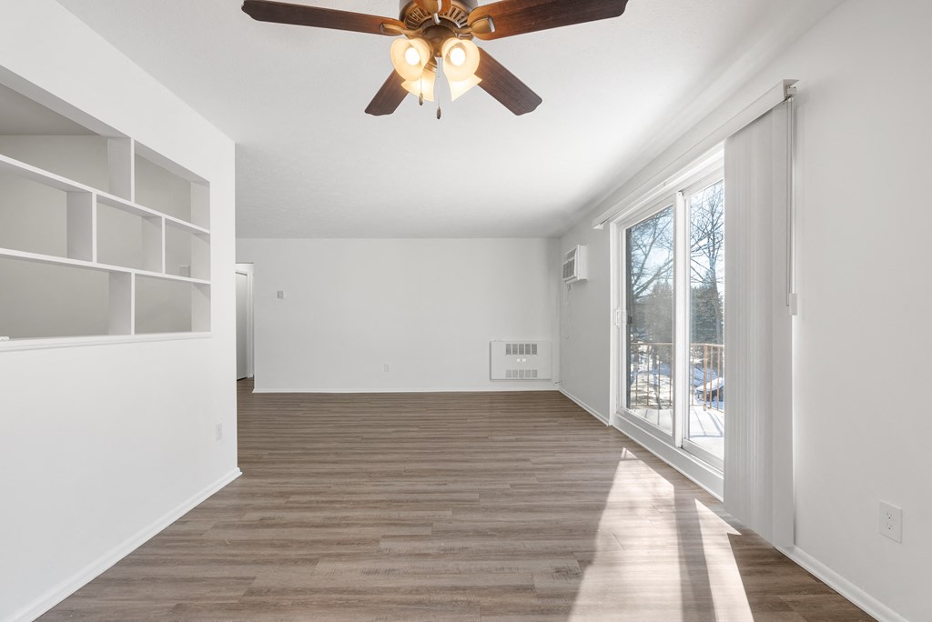 Bright updated Wynwood great room with a ceiling fan, plank-style flooring, and a sliding glass door to the balcony.