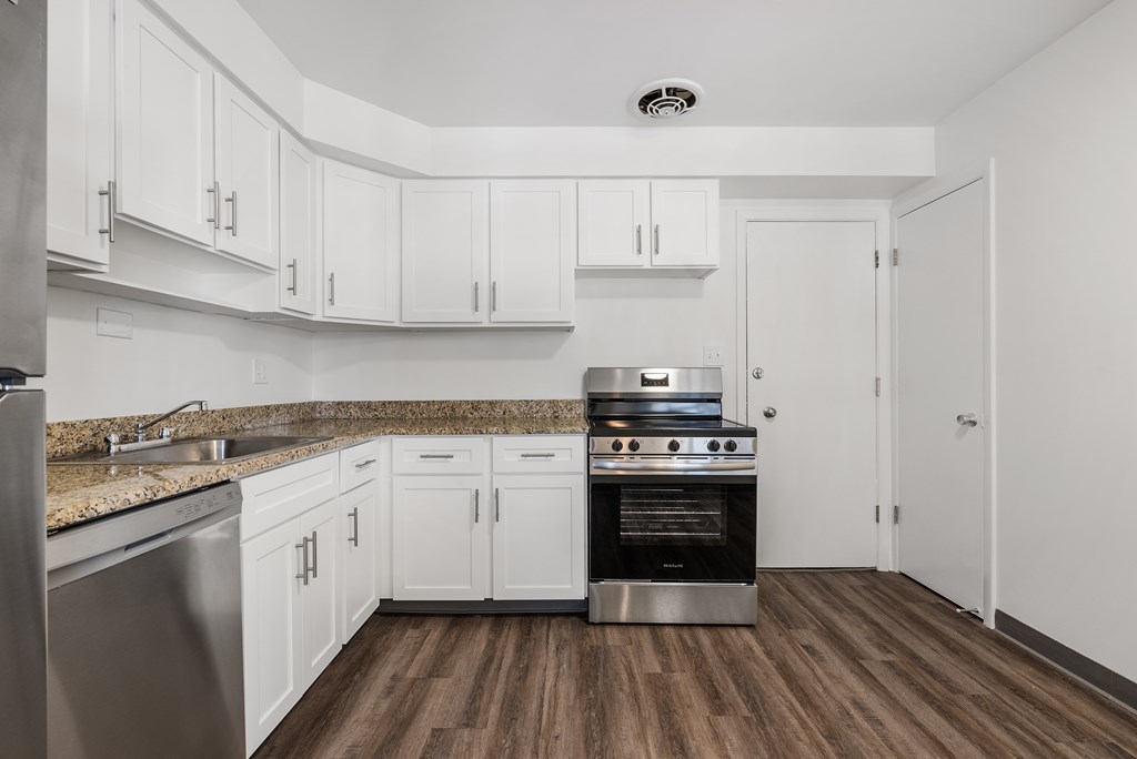 Updated Wynwood  kitchen with white cabinets, plank flooring,  and stainless steel appliances.