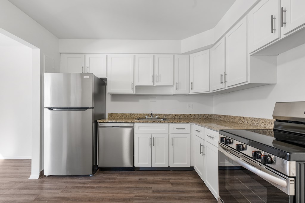 Wynwood renovated  kitchen with white cabinets, plank flooring, and stainless steel appliances.