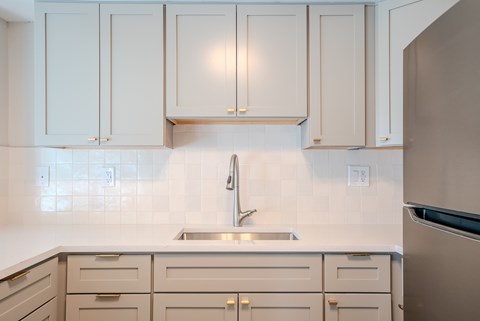 A kitchen with white cabinets and a stainless steel refrigerator.