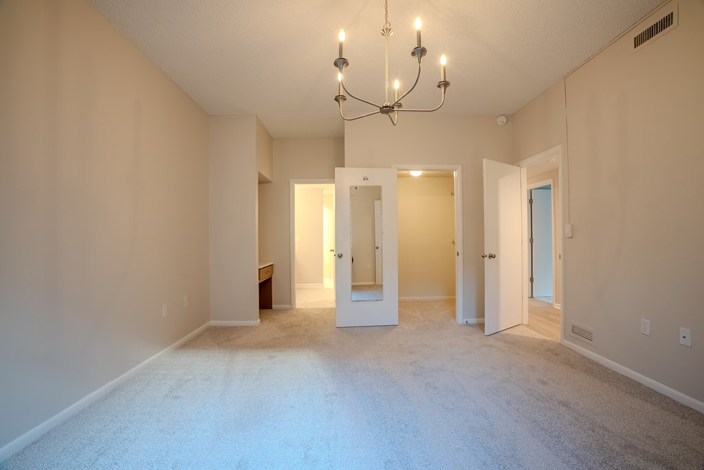 A large empty room with a chandelier and two doors.