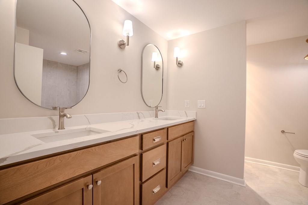 A bathroom with a white counter top and wooden cabinets.
