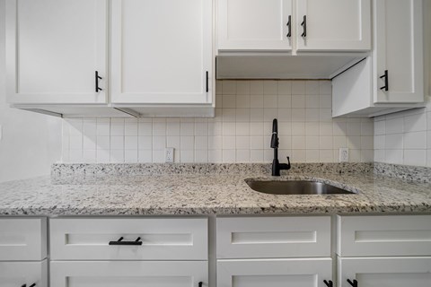 A kitchen with white cabinets and a granite countertop.