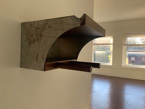 A custom bike rack is mounted on a white wall.
