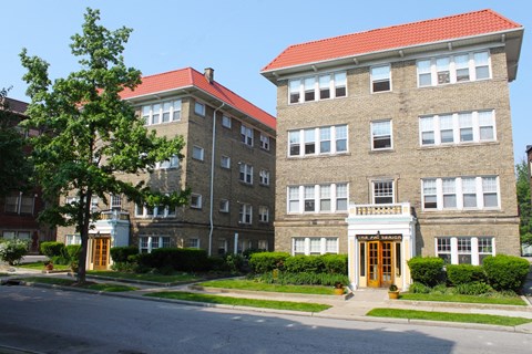 a view of two apartment buildings on the side of a street