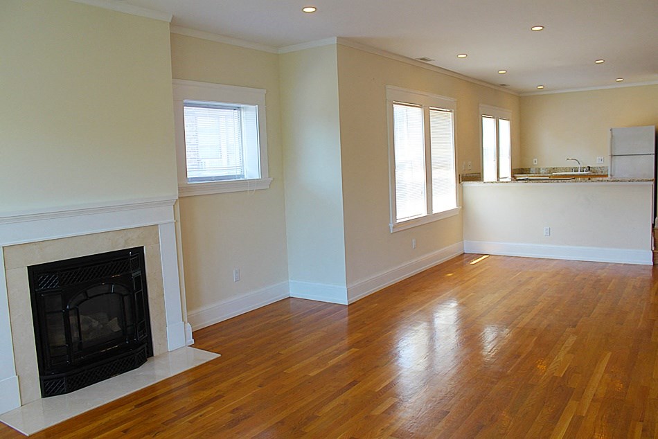 an empty living room with a fireplace and a hard wood floor