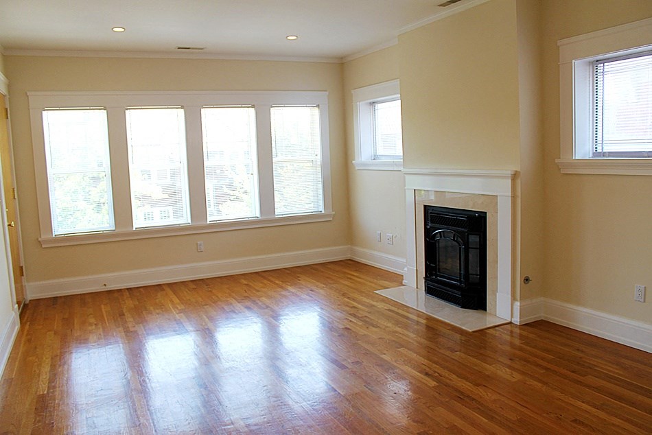an empty living room with a fireplace and wooden floors