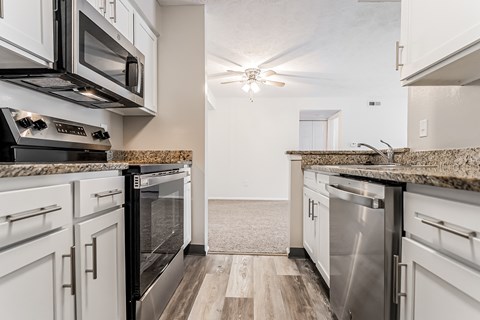 A kitchen with white cabinets and a granite countertop.