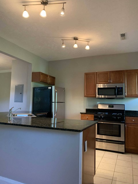 A kitchen with a black counter top and stainless steel appliances.
