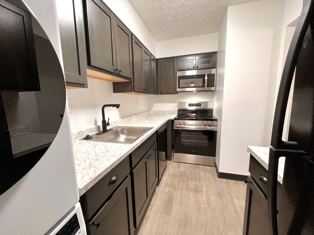 a kitchen with black cabinets and white countertops and a stainless steel sink and oven at Renova of Brunswick, Brunswick, 44212 