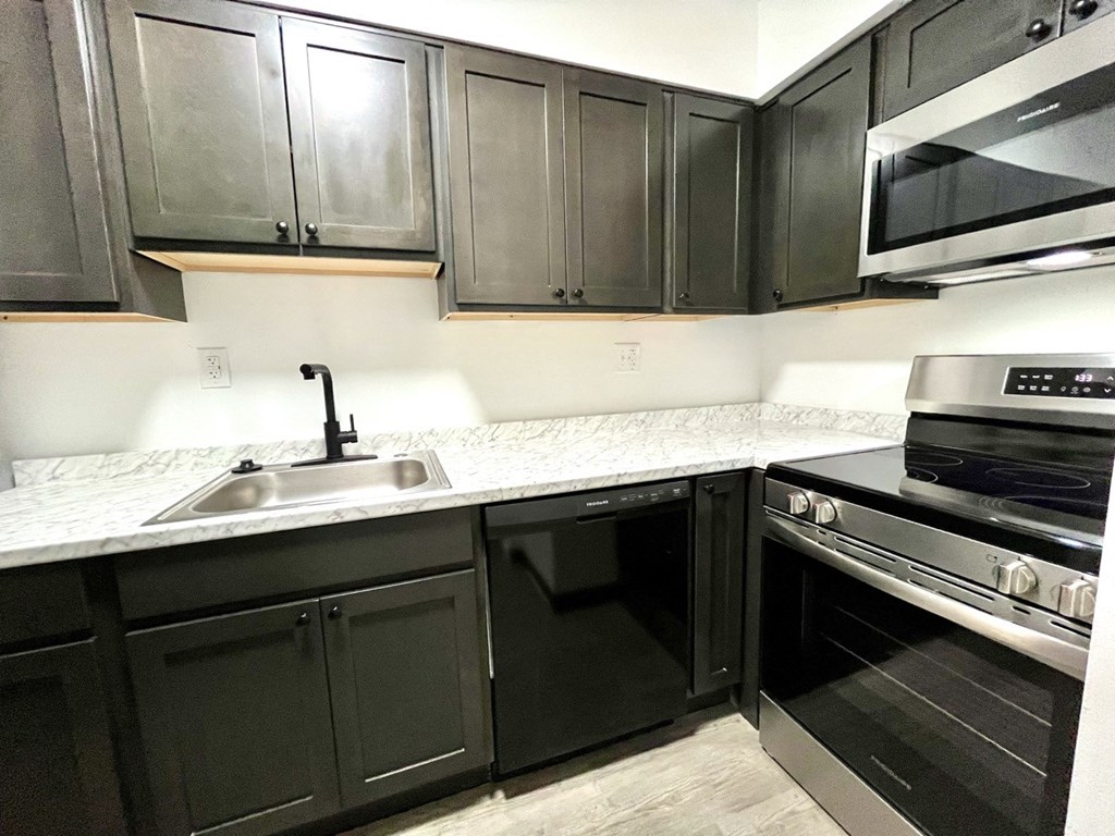 a kitchen with black cabinets and a sink and a microwave at Renova of Brunswick, Brunswick Ohio 