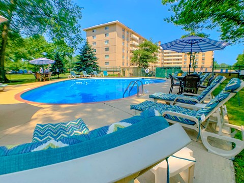 a swimming pool with lounge chairs and umbrellas in front of a building