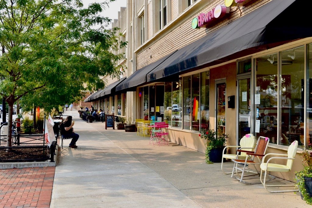 a city street with tables and chairs outside a store