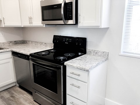 a kitchen with a stove and a microwave and white cabinets