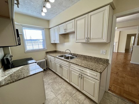 A kitchen with white cabinets and a granite countertop.