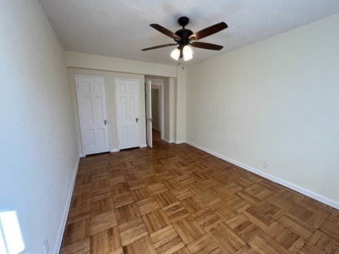 A room with a ceiling fan and wooden flooring.
