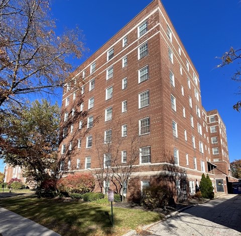 A tall red brick building with many windows and a sign in front.