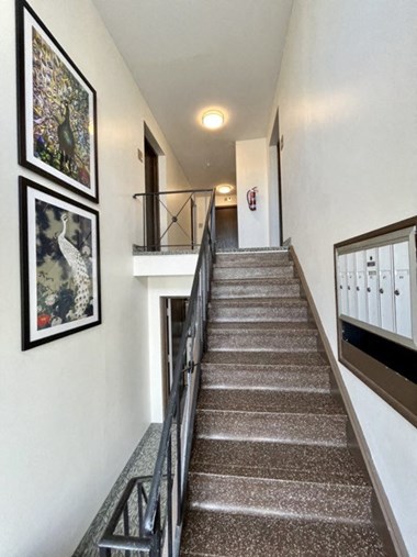 a stairway with a metal railing and pictures on the wall