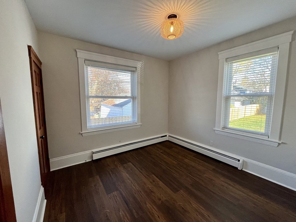 an empty room with wooden floors and two windows
