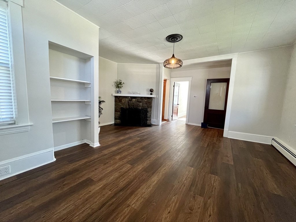 a living room with white walls and a fireplace and wooden floors