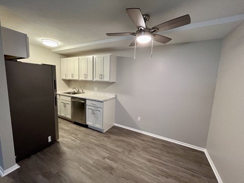 an empty room with a kitchen and a ceiling fan