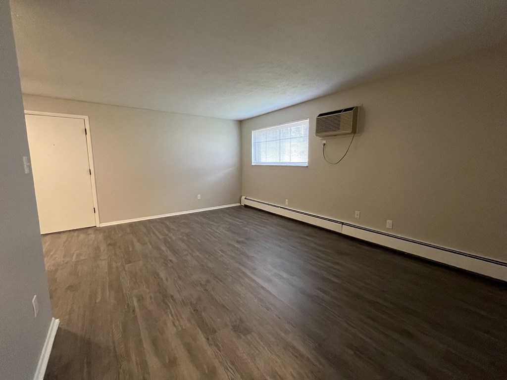 an empty living room with wood floors and an air conditioner