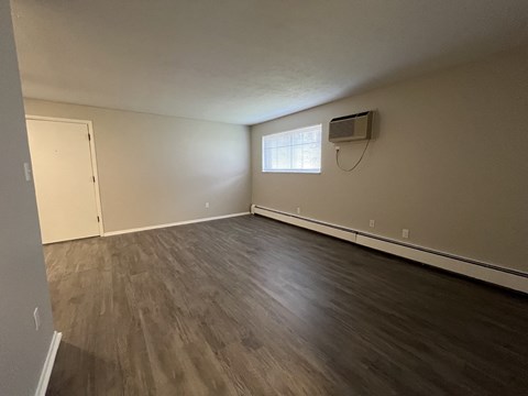 an empty living room with wood floors and an air conditioner