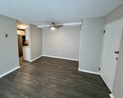 an empty living room with wood flooring and a ceiling fan