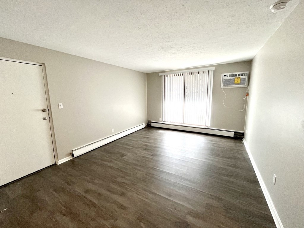 an empty living room with plank style flooring and white walls