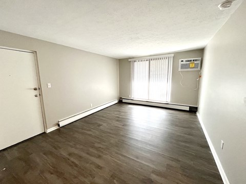 an empty living room with plank style flooring and white walls