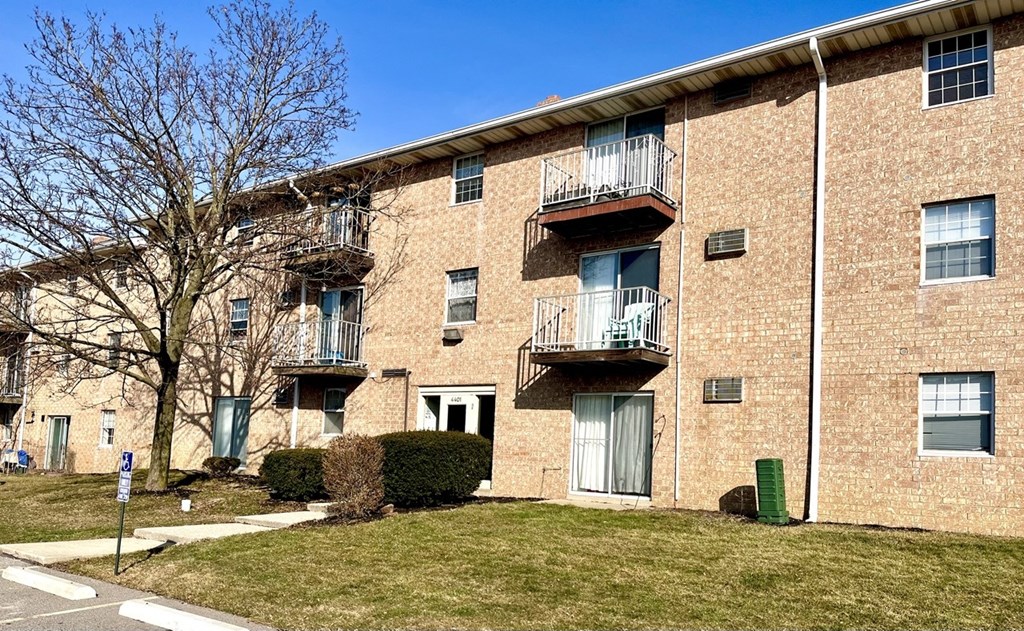 a brick apartment building with balconies and a lawn